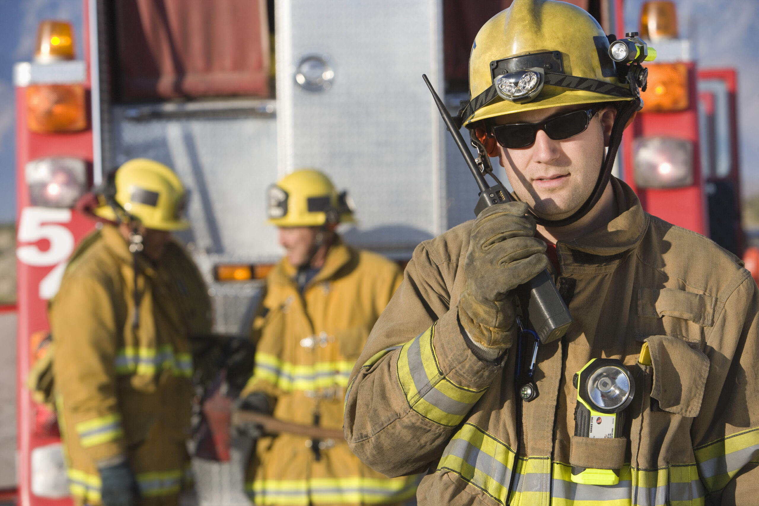Portrait,Of,A,Firefighter,Talking,On,Radio,With,Colleagues,Standing